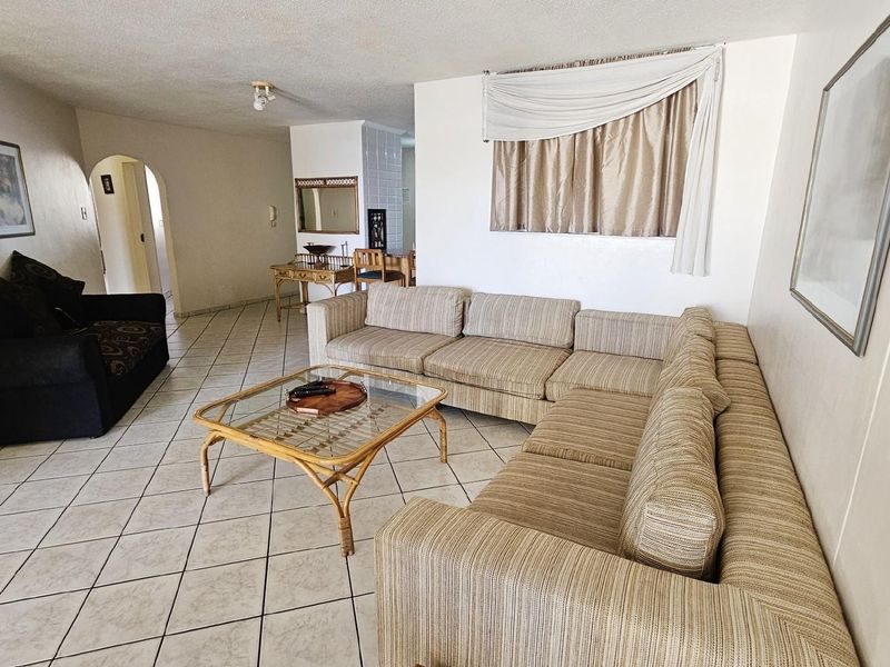 Spacious open-plan living area featuring neutral ceramic floor tiles and a functional layout, providing a versatile space for relaxation and entertaining.