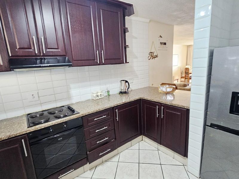 A functional kitchen featuring dark wood cabinetry, granite countertops, a built-in oven and hob, and white subway tile backsplash.