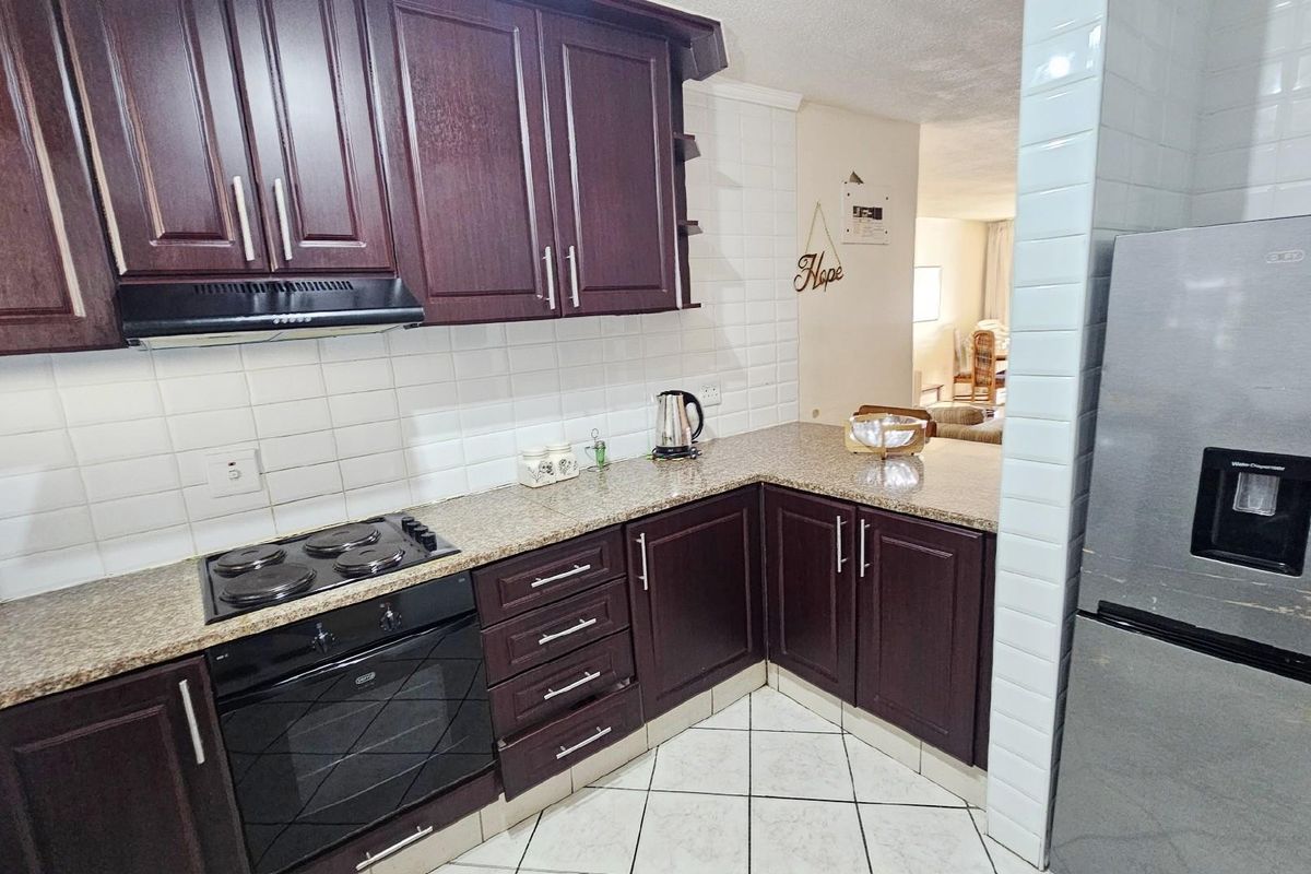 A functional kitchen featuring dark wood cabinetry, granite countertops, a built-in oven and hob, and white subway tile backsplash.