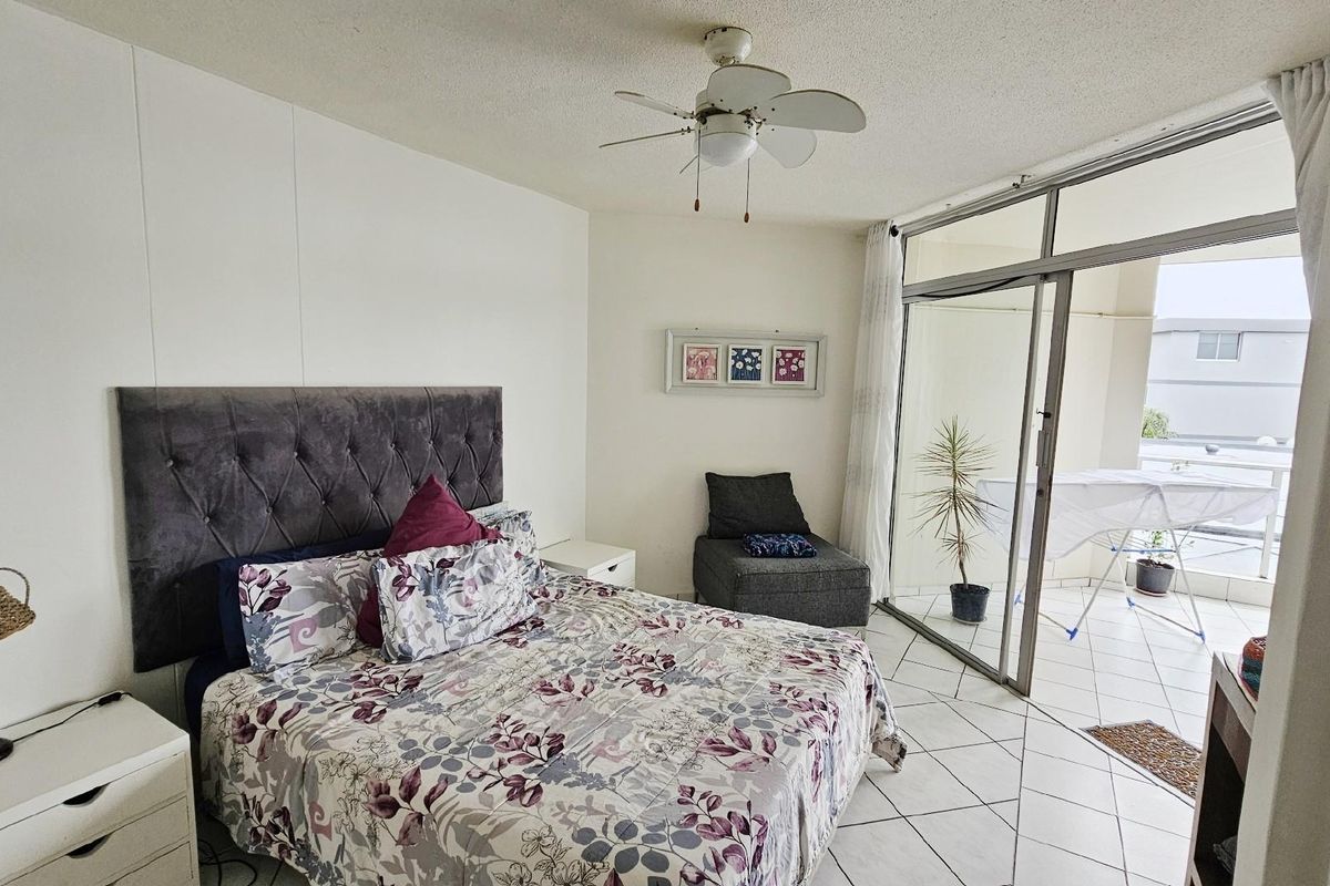 A bedroom featuring tiled flooring and a sliding glass door providing direct access to an attached balcony.