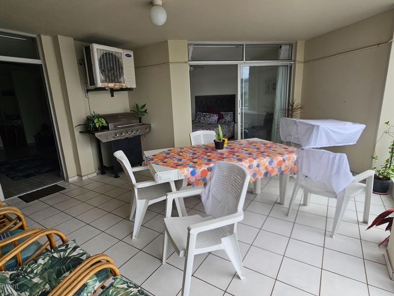 A covered patio area featuring tiled flooring, a wall-mounted air conditioning unit, and direct access to the interior living spaces.