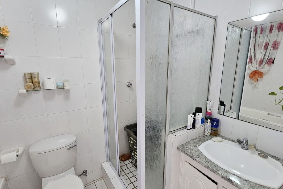 A functional bathroom featuring a shower enclosure, vanity with granite countertop, integrated sink, and wall-mounted mirror.