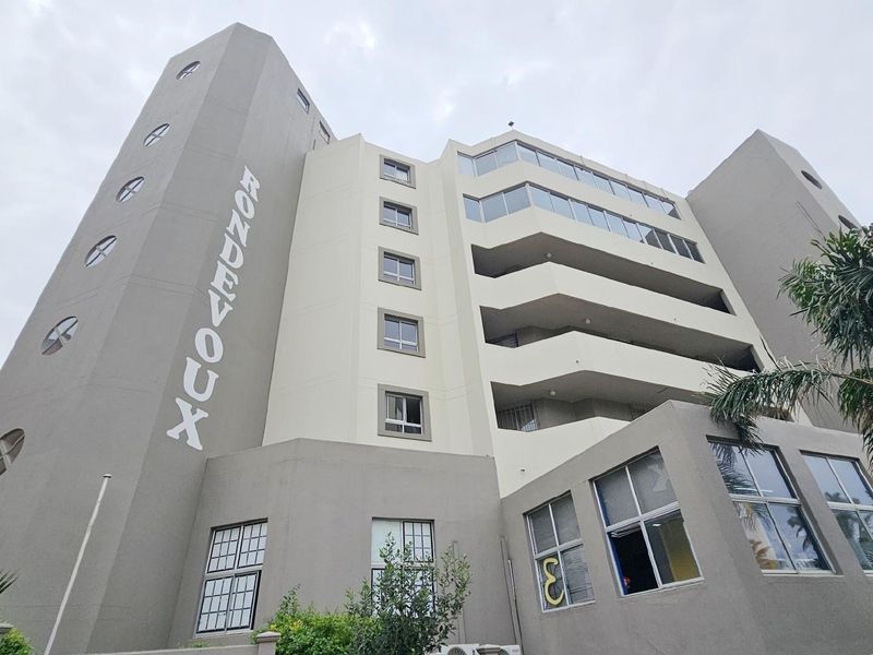 Low-angle exterior view of the RondeVoux apartment building, showcasing its multi-story facade, architectural design, and integrated balcony structures.