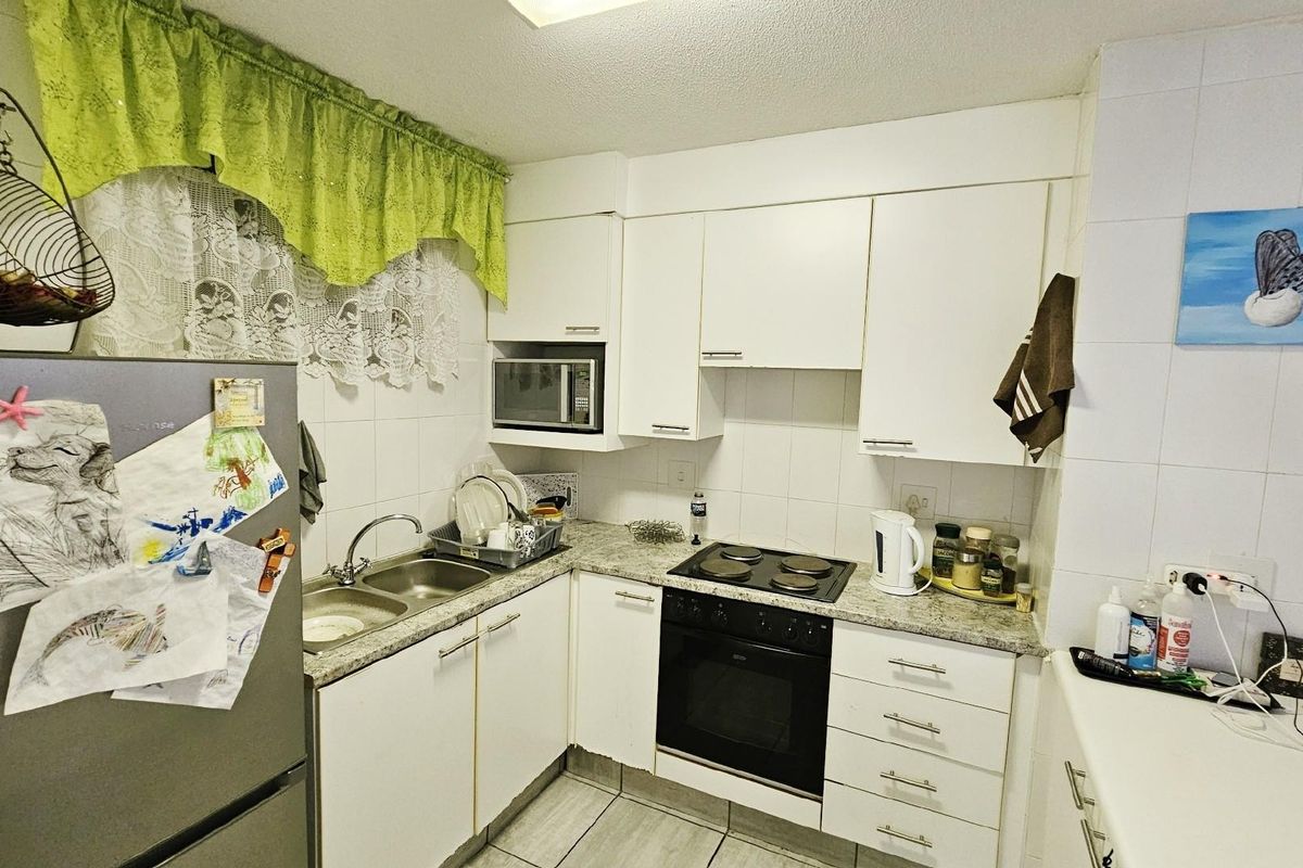 Compact kitchen featuring white cabinetry, granite-look countertops, a built-in oven with electric hob, and a double-basin stainless steel sink.