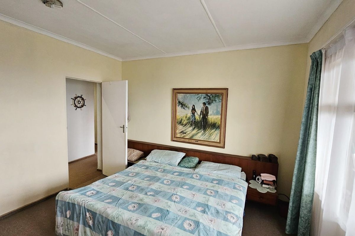 A bedroom featuring built-in headboard cabinetry, carpeted flooring, and access to an adjoining hallway.