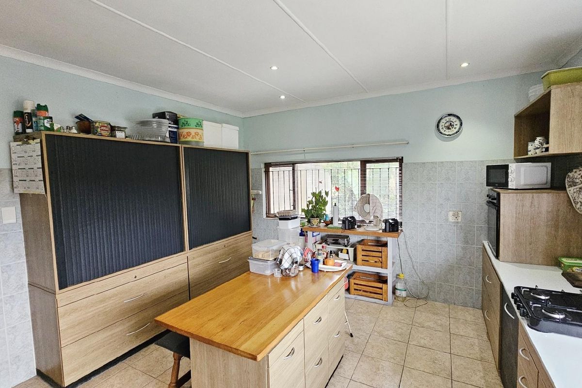 Functional kitchen featuring built-in cabinetry, a central island, tiled flooring, and a built-in oven with gas hob.