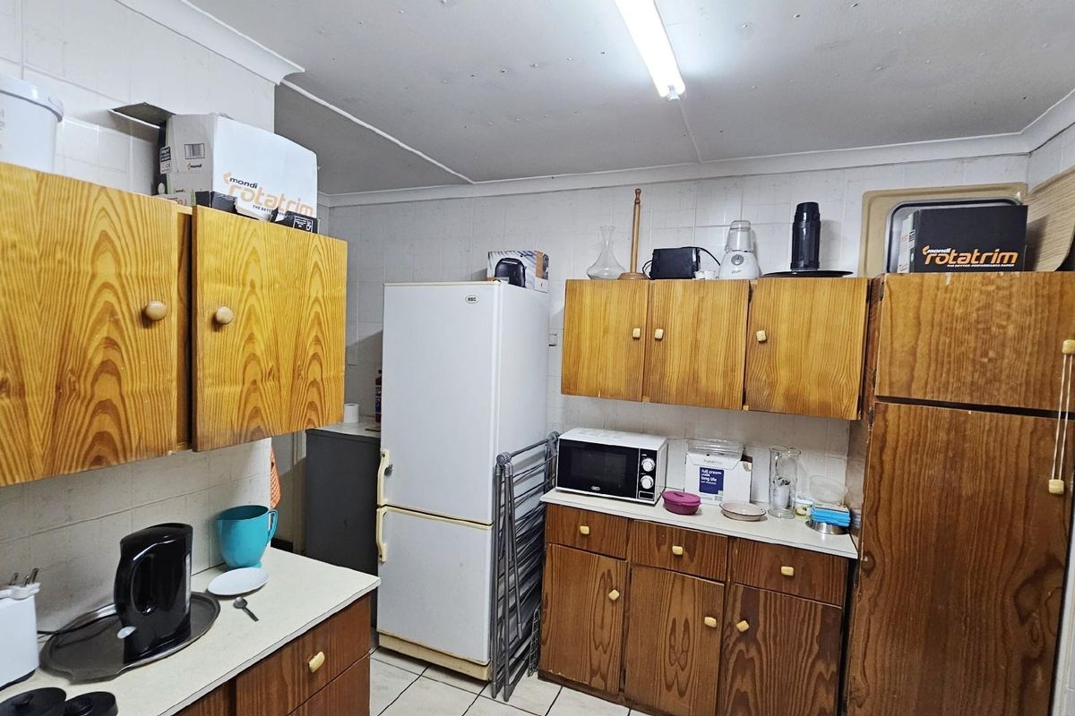 A functional kitchen featuring traditional wood-grain cabinetry, tiled walls, and tiled flooring, providing ample storage and workspace for daily meal preparation.