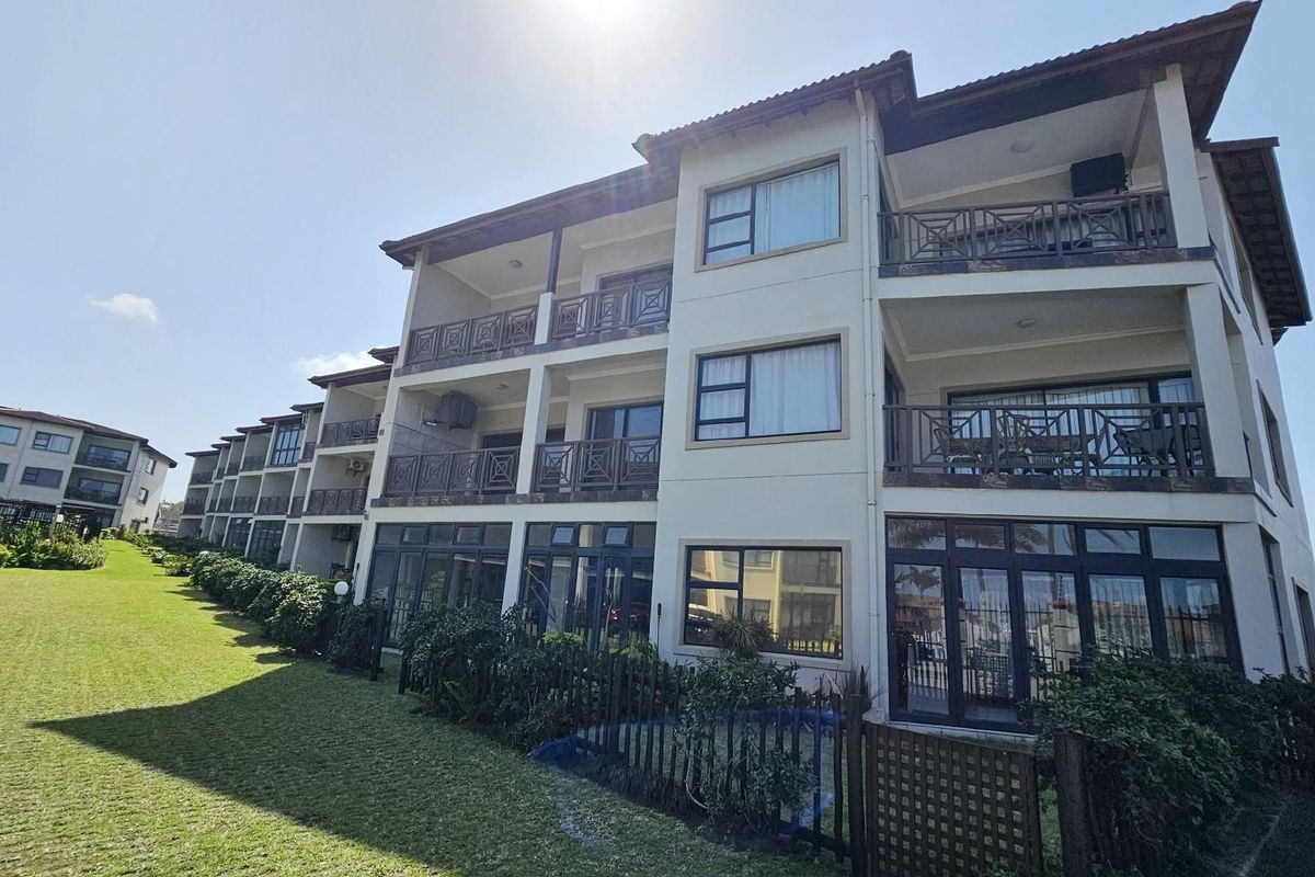 A view of the apartment complex exterior featuring multi-level balconies, large windows, and well-maintained landscaped grounds.
