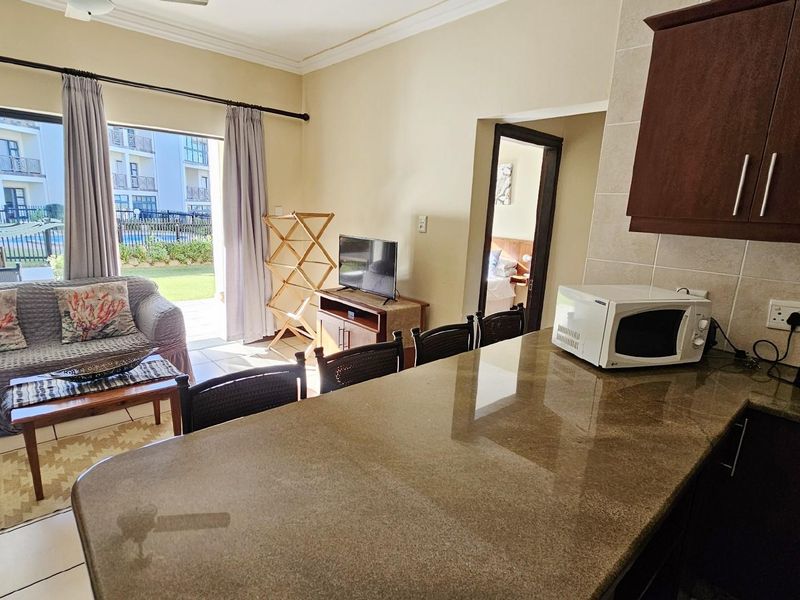 Open-plan living area featuring a kitchen with granite countertops and a seamless transition to a patio with garden views.