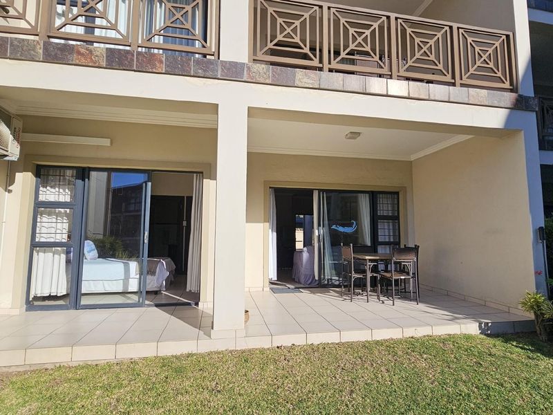 A ground-floor patio area featuring tiled flooring, sliding glass doors providing access to the interior, and an external air conditioning unit.