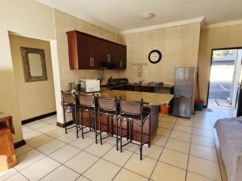Open-plan kitchen and living area featuring dark wood cabinetry, granite countertops, breakfast bar, and tiled flooring throughout.