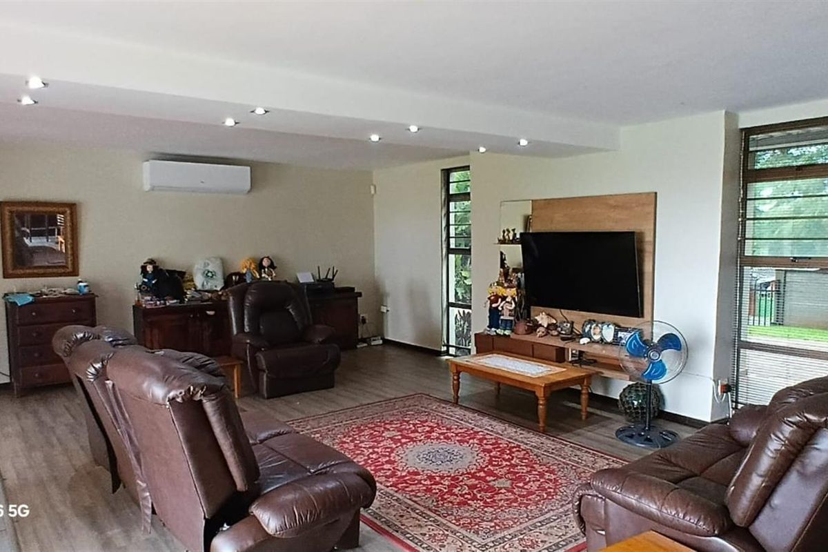 Spacious living room featuring recessed ceiling lighting, a wall-mounted air conditioning unit, and large windows providing natural light.