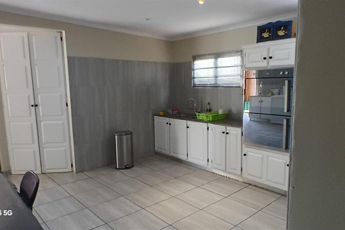 A functional kitchen featuring white cabinetry, built-in oven, tiled flooring, and a tiled splashback, offering a practical layout for daily meal preparation.