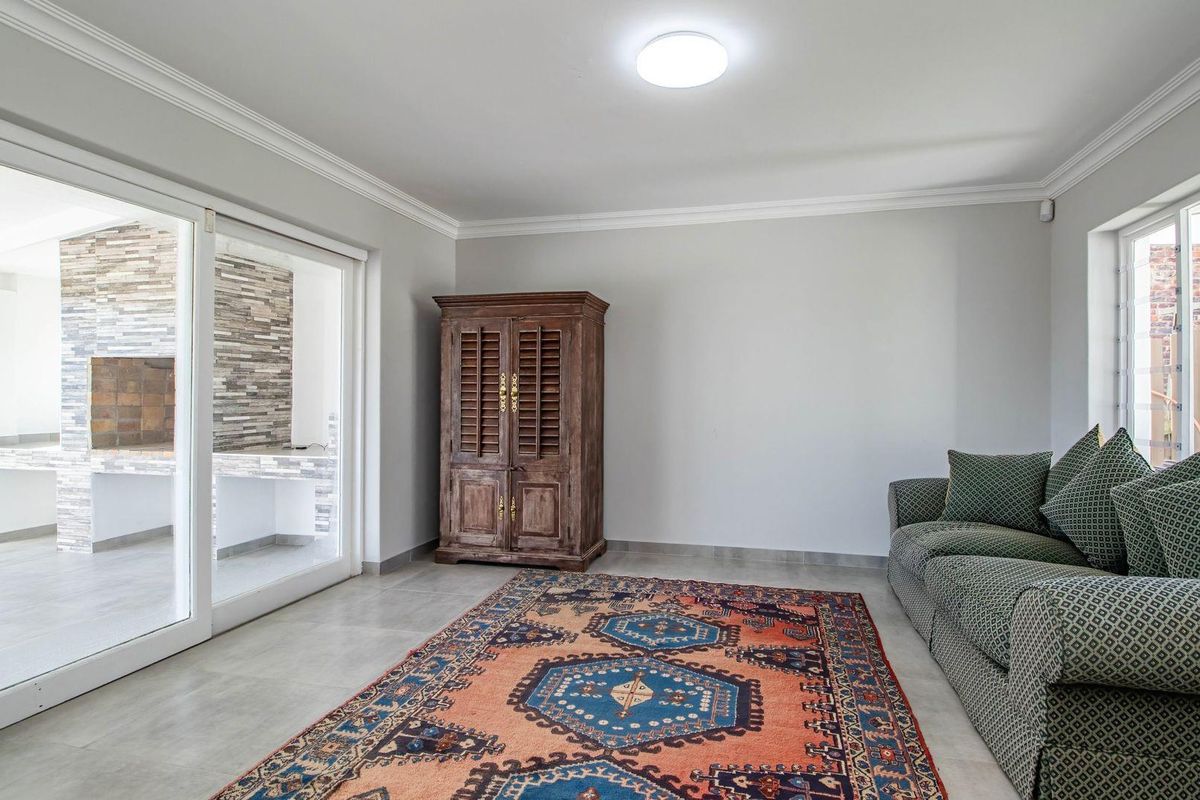 A bright living room featuring tiled flooring, crown molding, and large sliding glass doors that open onto a covered patio area.
