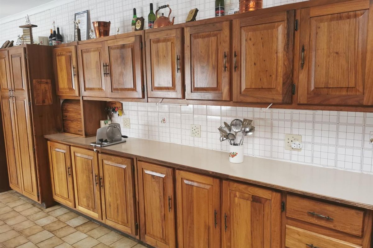 A traditional kitchen featuring extensive solid wood cabinetry, tiled splashbacks, and durable floor tiles, offering a classic aesthetic with ample storage space.