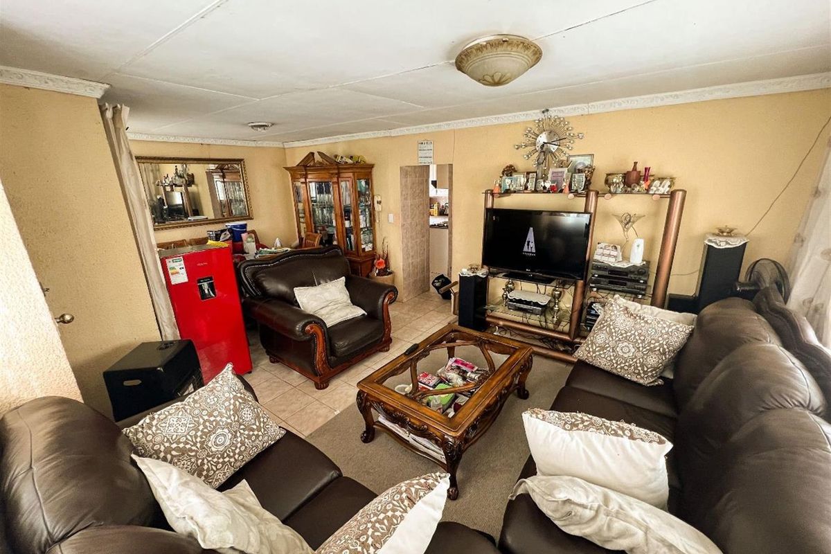 A living room featuring tiled flooring and ceiling cornice detailing, requiring cosmetic updates to the ceiling and wall finishes.