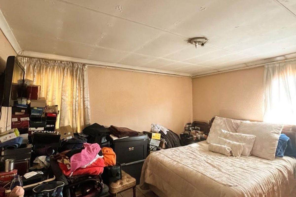 A bedroom featuring tiled flooring and ceiling panels, requiring cosmetic updates to improve the overall condition and appeal of the space.