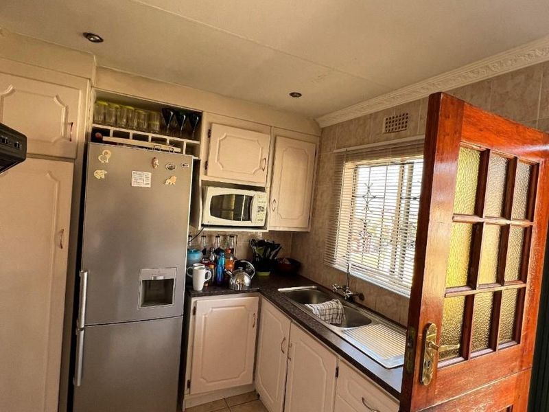A functional kitchen featuring built-in cabinetry, tiled flooring, and a stainless steel sink, offering a practical layout with natural light from the window.