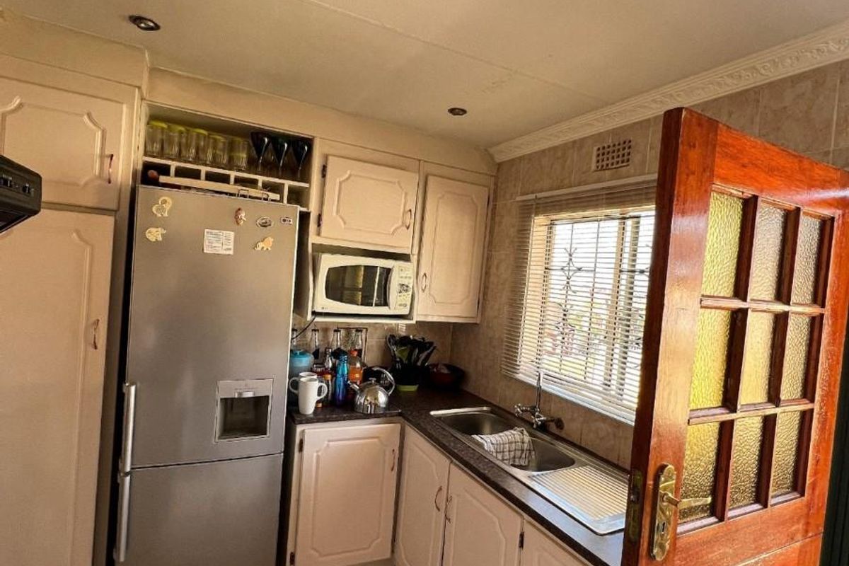 A functional kitchen featuring built-in cabinetry, tiled flooring, and a stainless steel sink, offering a practical layout with natural light from the window.