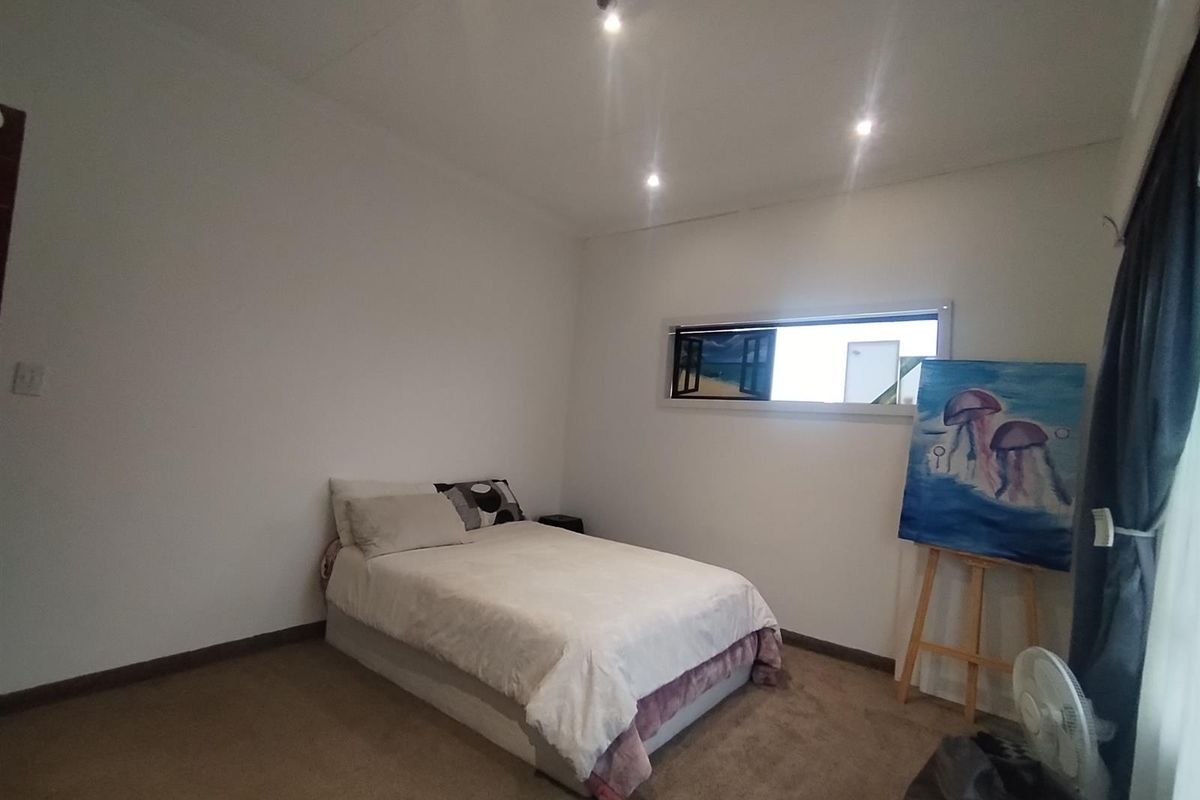 A simple bedroom featuring neutral walls, carpeted flooring, recessed ceiling lighting, and a horizontal window.