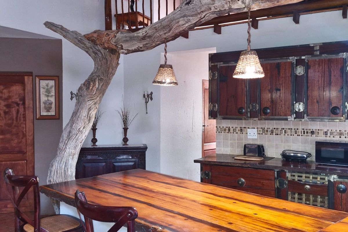 Rustic kitchen featuring custom dark wood cabinetry, integrated breakfast bar, and unique natural timber structural elements.