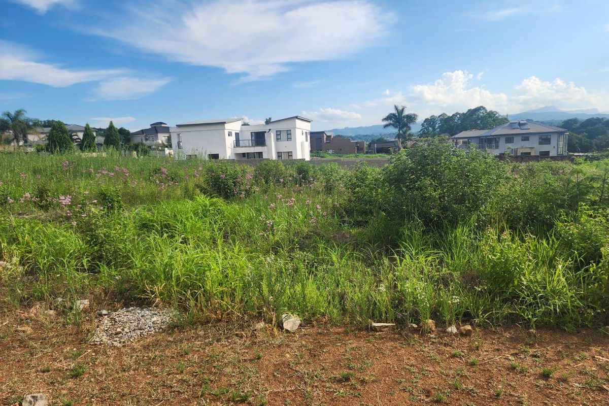 A vacant residential plot featuring natural vegetation and surrounding neighborhood views, offering a blank canvas for future development.