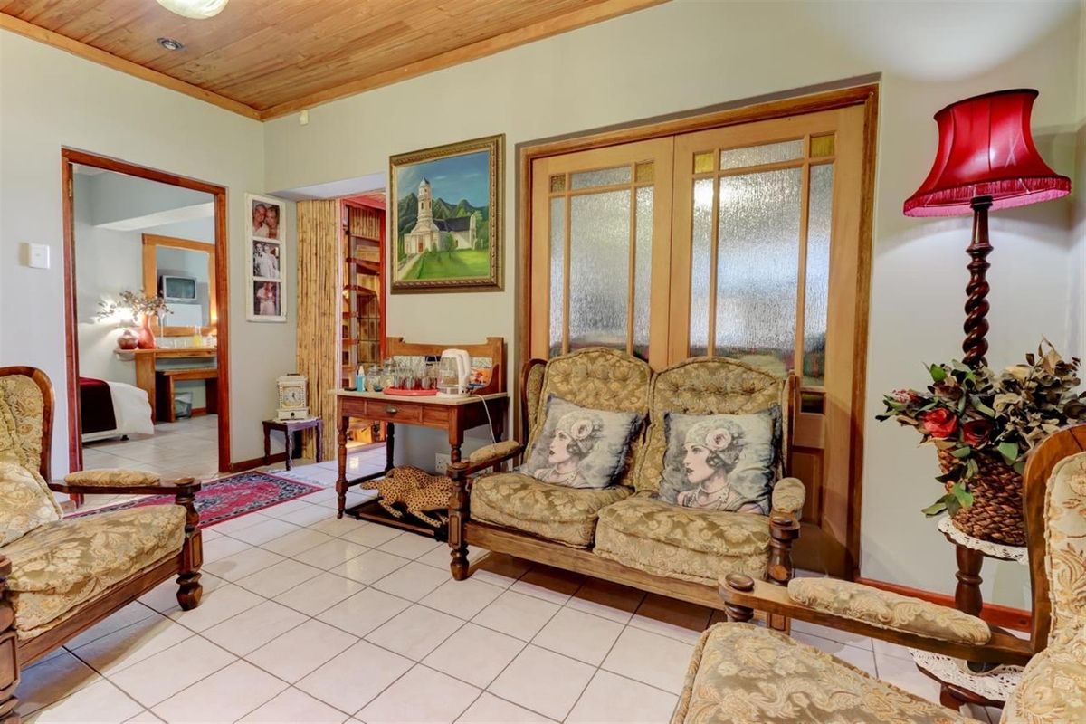 A living room featuring tiled flooring, a timber-clad ceiling, and double doors with textured glass panels leading to an adjacent space.