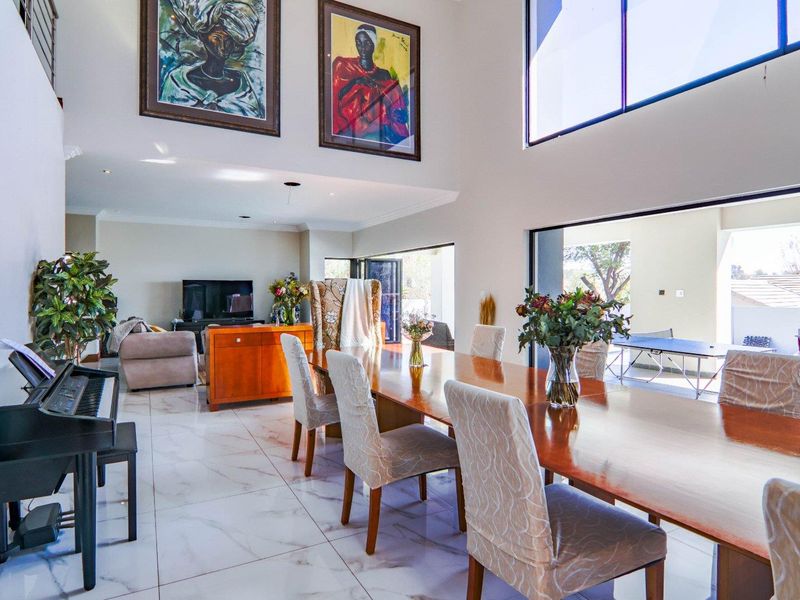 Spacious open-plan living and dining area featuring double-volume ceilings, large format tiled flooring, and seamless indoor-outdoor flow through expansive sliding glass doors.