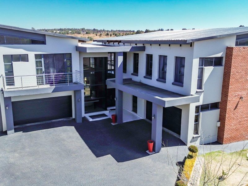 Modern double-story residence featuring a contemporary architectural design, paved driveway, double garage, and a prominent brick feature wall.