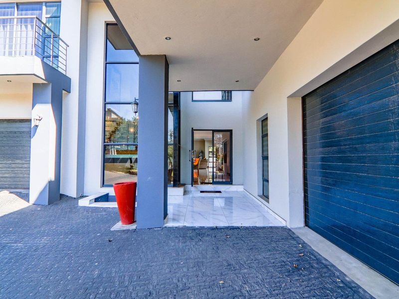 Modern front elevation featuring a paved driveway, double garage, covered entrance with tiled porch, and large glass windows.