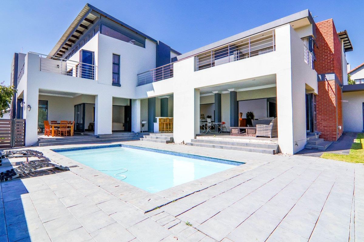 Spacious rear exterior featuring a swimming pool, expansive tiled patio, covered entertainment areas, and upper-level balconies with modern architectural design.