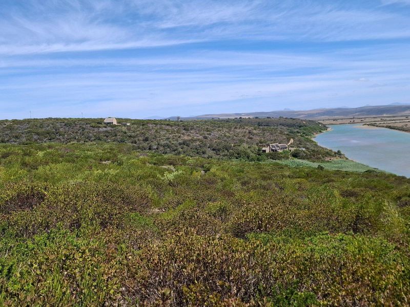 A scenic landscape view of the farm property, featuring natural vegetation, rolling hills, and a river flowing alongside the estate.