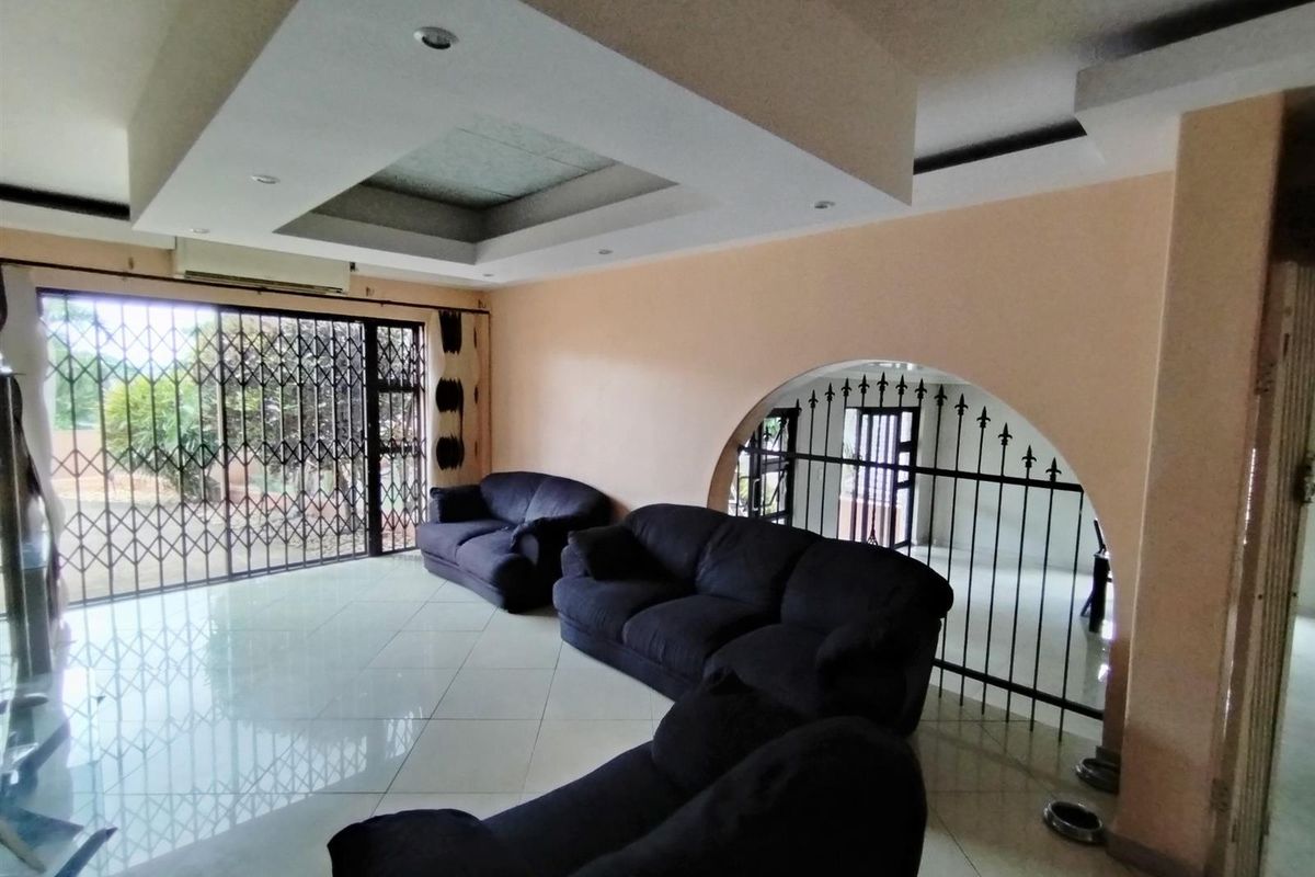 Spacious living area featuring a recessed tray ceiling with downlights, large sliding glass doors with security gates, and polished floor tiles.