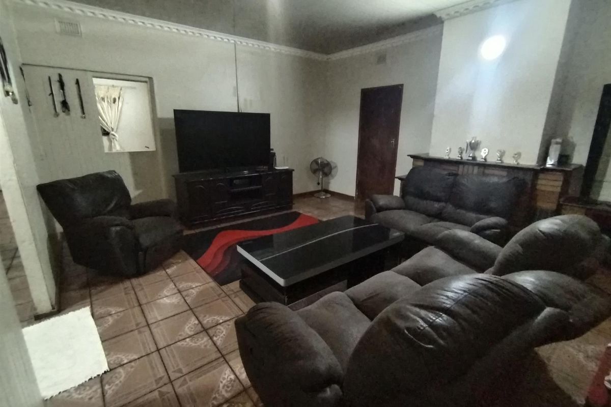 A living room featuring tiled flooring, decorative ceiling cornices, and a built-in fireplace mantle.