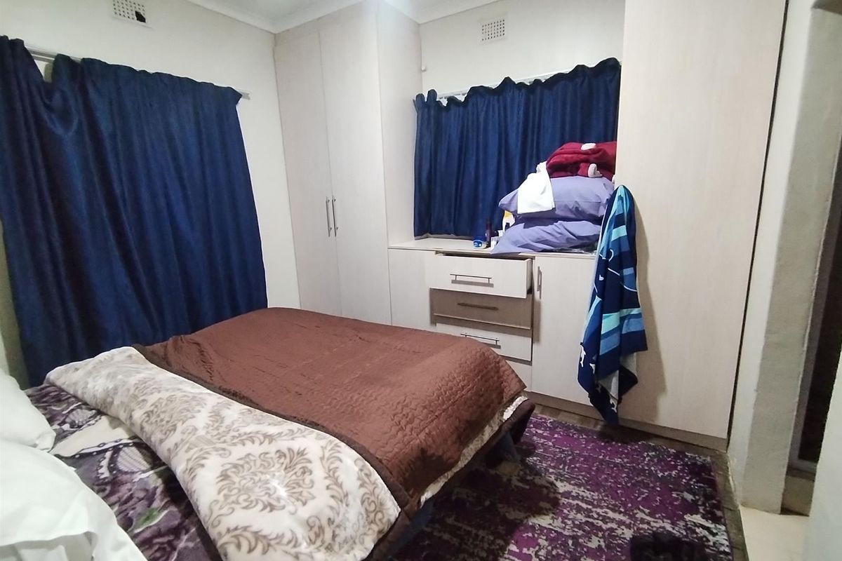A bedroom featuring built-in cupboards with integrated storage and window treatments.