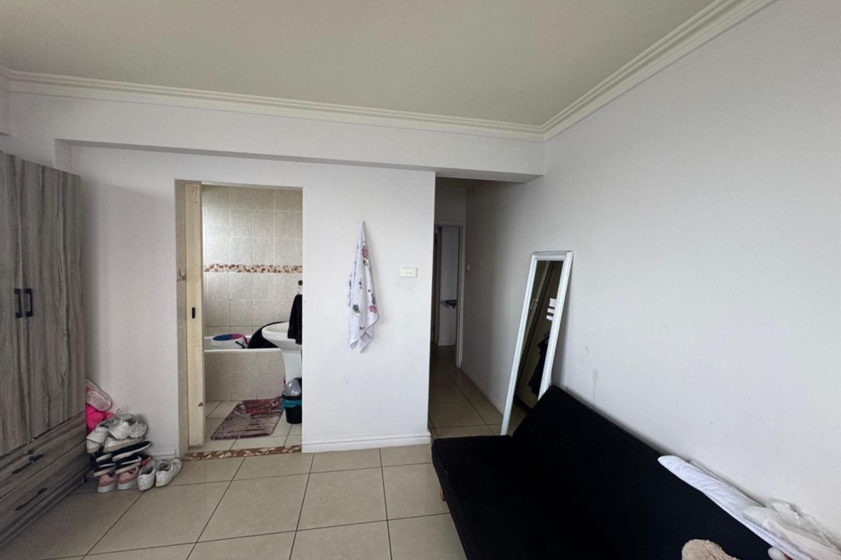A bedroom featuring tiled flooring, crown molding, and an en-suite bathroom with a bathtub.