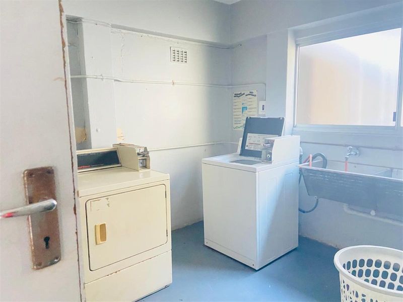 Functional laundry room featuring a utility sink, dedicated plumbing connections, and space for laundry appliances with natural light from a window.