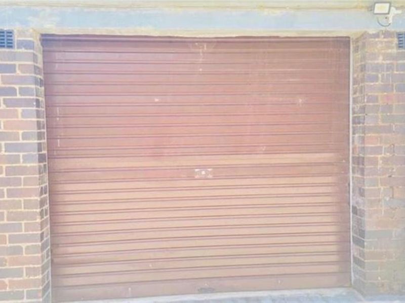A secure single garage unit featuring a brown roller shutter door and traditional brick exterior construction.