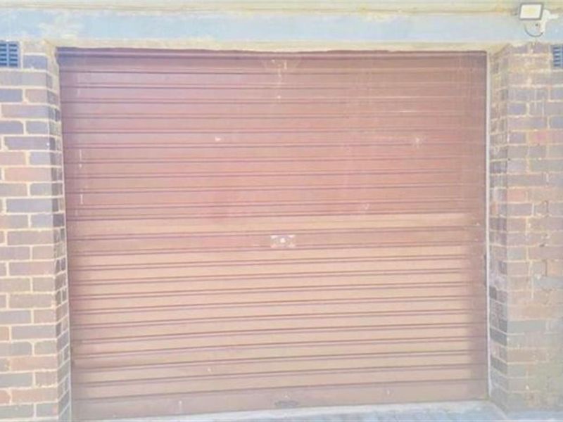 A standard single-car garage featuring a brown roller door and brick exterior construction.