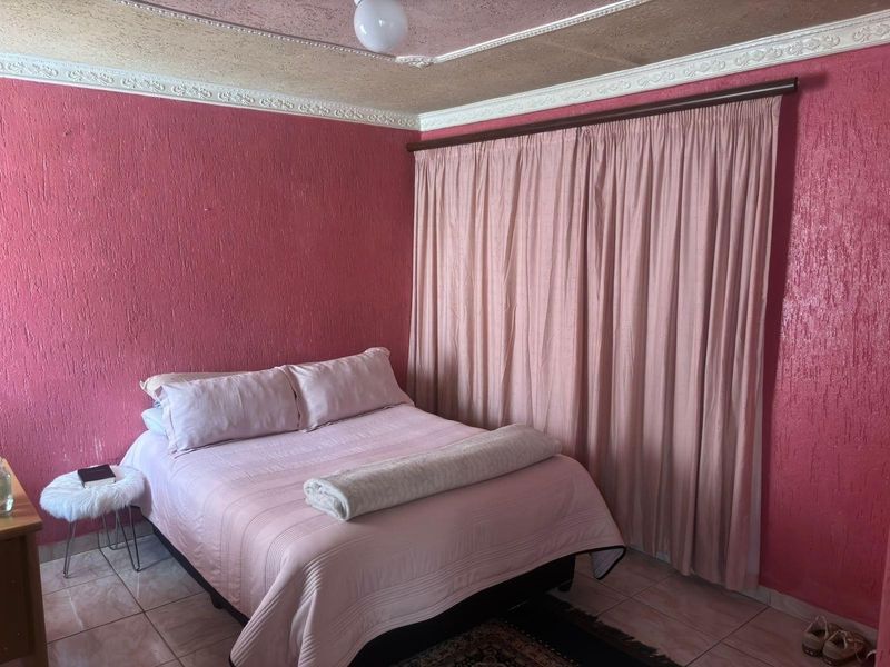 A bedroom featuring textured walls, decorative ceiling cornices, and tiled flooring, offering a dated aesthetic ready for modernization.