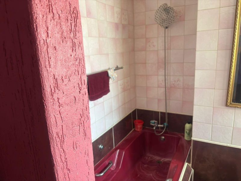 A dated bathroom featuring a built-in bathtub with shower mixer and tiled wall finishes.