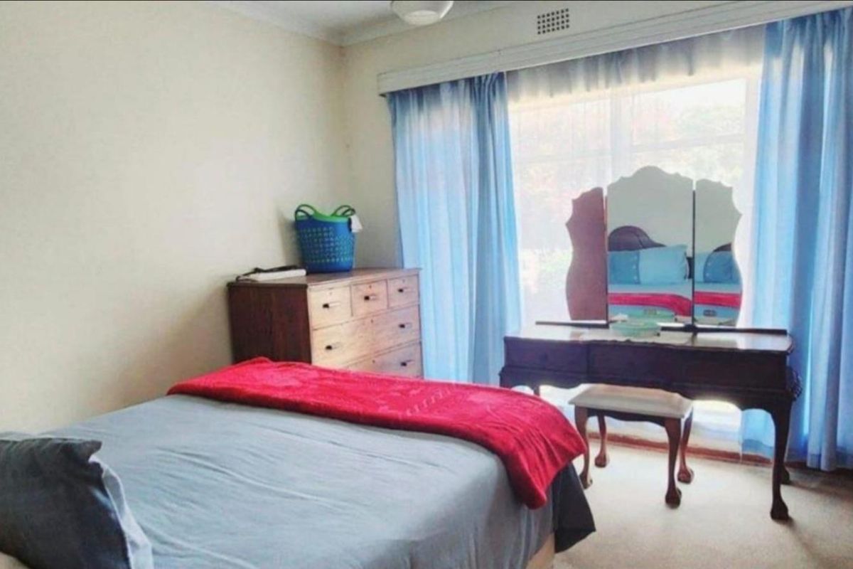 A standard bedroom featuring carpeted flooring and a large window with curtain tracks.
