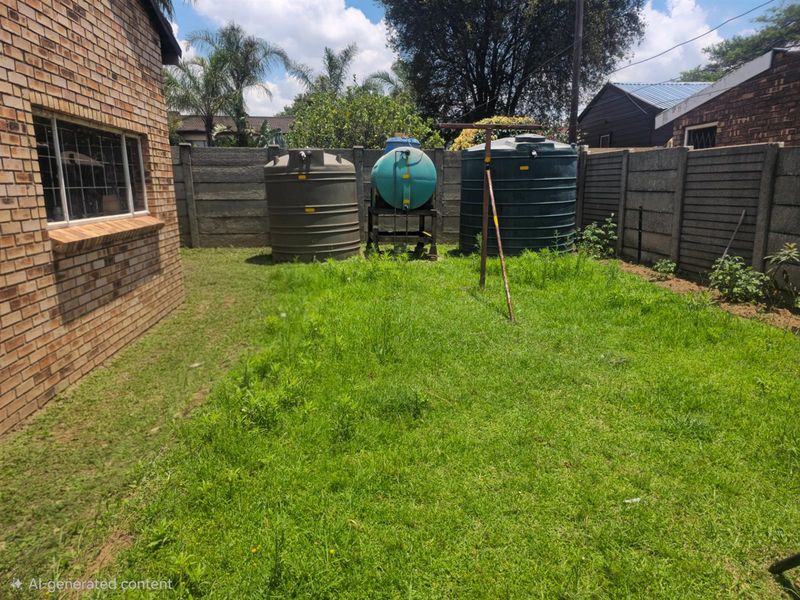 A rear garden area featuring a brick exterior wall, grass lawn, and multiple large water storage tanks positioned against the boundary wall.