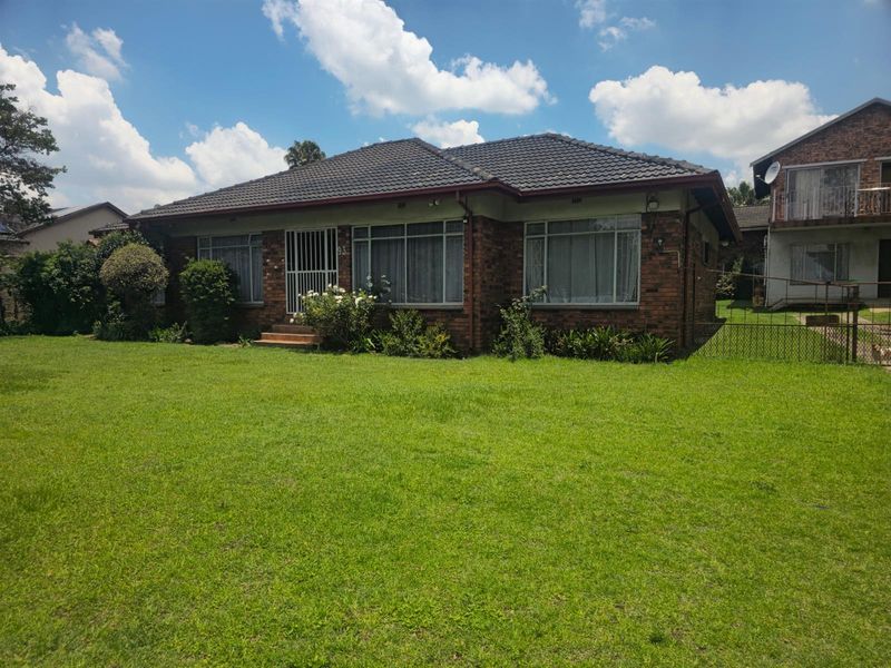 A single-story brick house featuring a tiled roof, large windows, and a spacious front lawn in a residential setting.