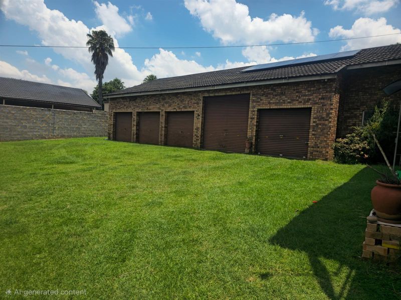 A spacious rear garden area featuring a large brick-built garage structure with multiple roller shutter doors and roof-mounted solar panels.