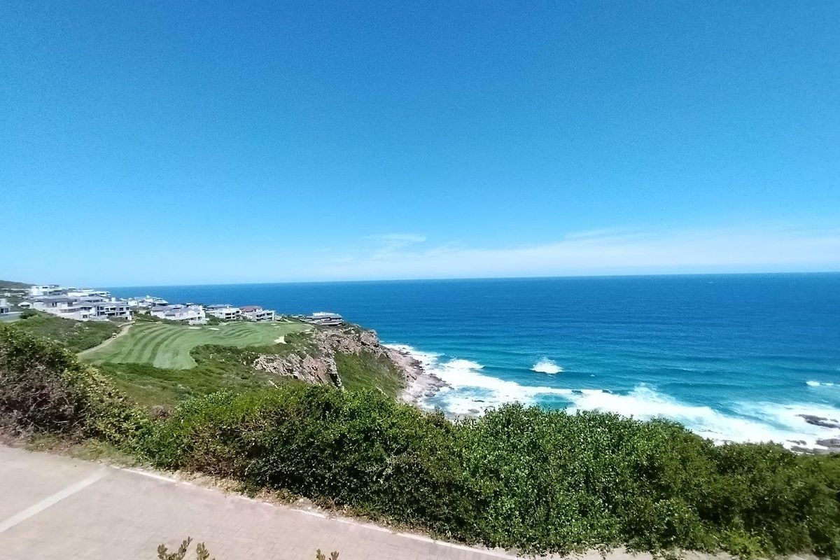 A scenic coastal view overlooking the ocean, rugged cliffs, and a nearby golf course estate.