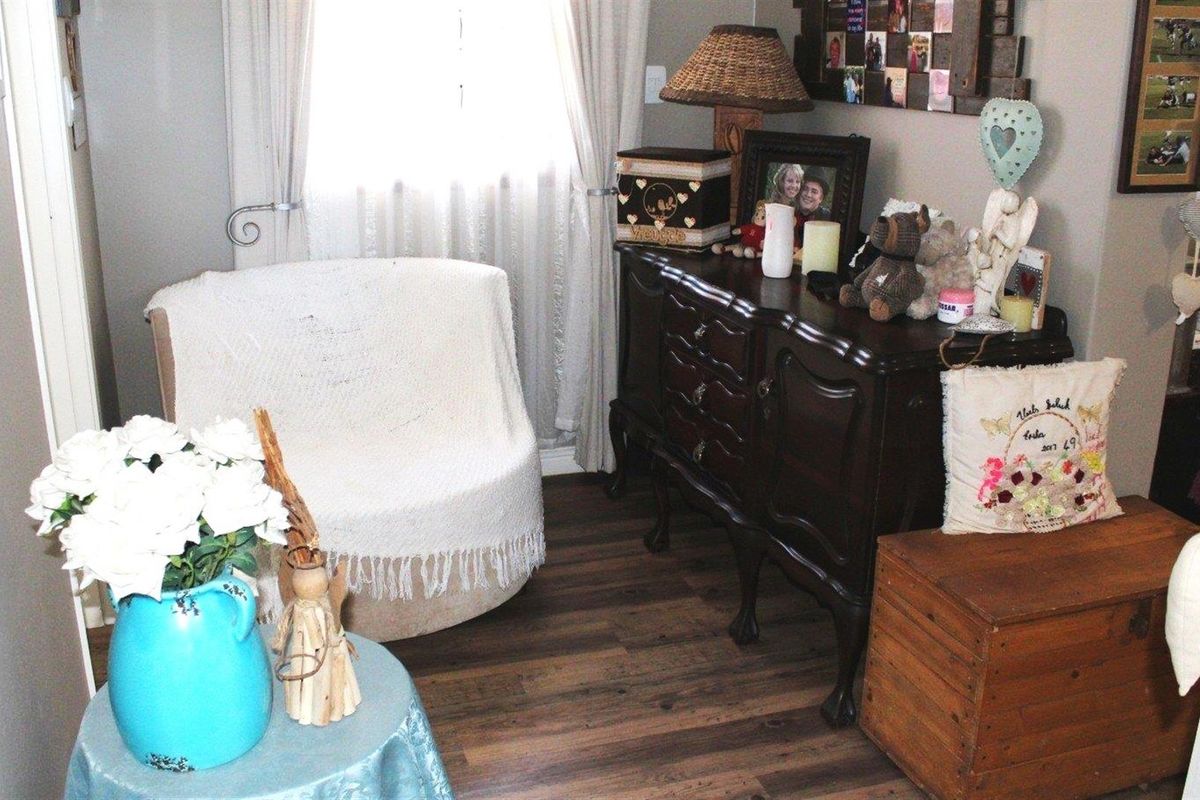 A cozy living area featuring durable laminate flooring and natural light through a window with installed curtain rods.