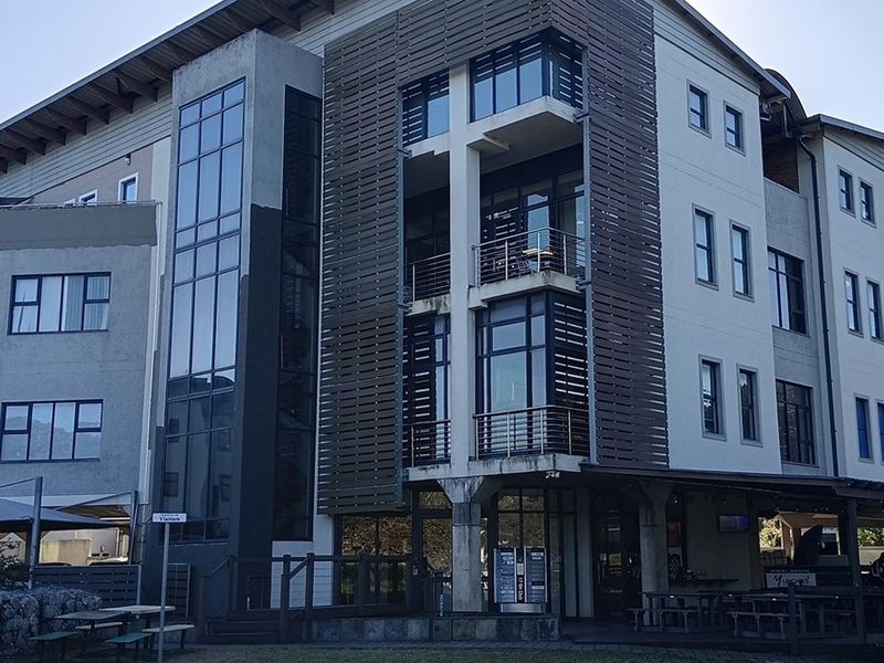 Modern multi-story office building featuring a glass facade, timber-slat screening, and integrated balconies, showcasing contemporary architectural design and professional exterior finishes.