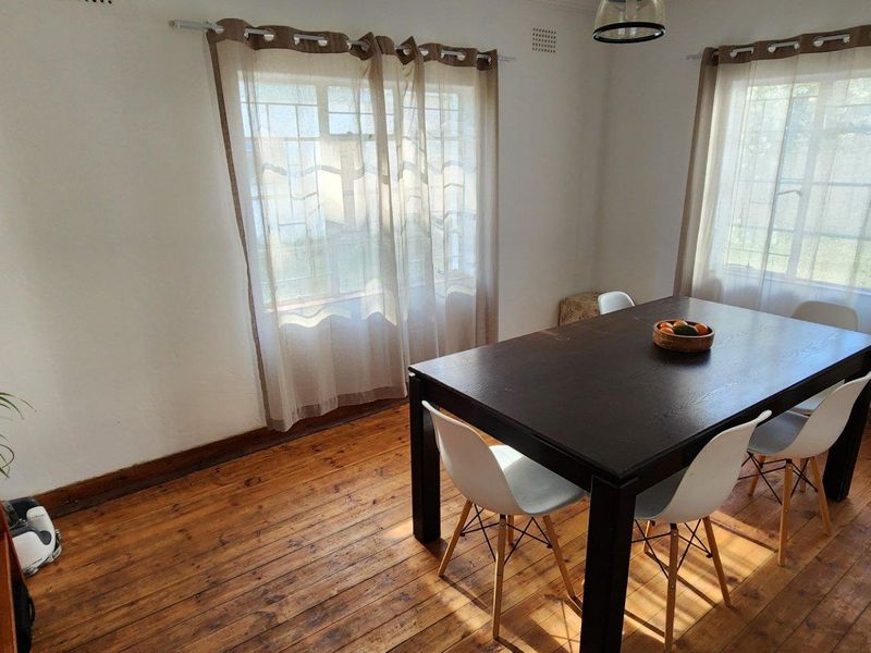 A dining room featuring original timber flooring and large steel-framed windows that provide natural light.