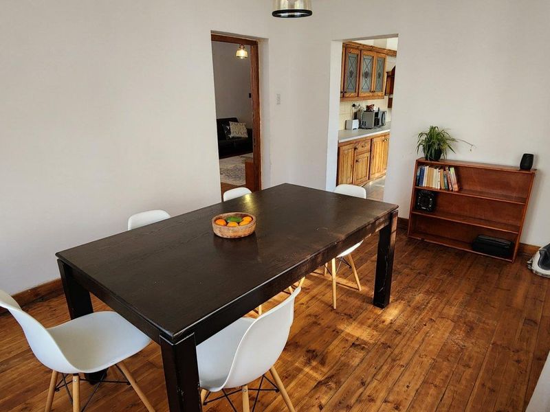 Dining room featuring warm hardwood flooring and an open archway leading to the kitchen area, providing a functional and connected living space.